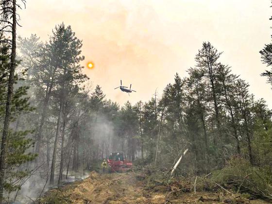 This image provided by the The Michigan Department of Natural Resources shows emergency personnel, aircraft and heavy equipment being used to suppress the wildfire near Grayling, MI, June 3, 2023. THE MICHIGAN DEPARTMENT OF NATURAL RESOURCES VIA AP