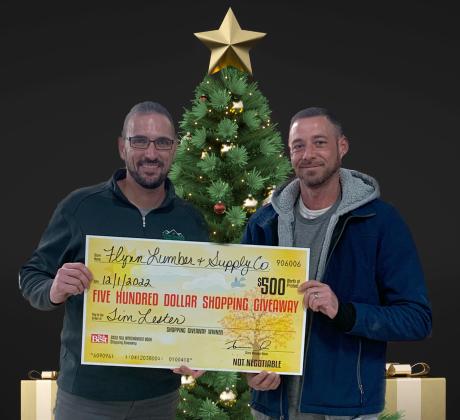 Jerram Dee (left) presents the $500 shopping giveaway check to Tim Lester of Gladwin, one of the two winners.
